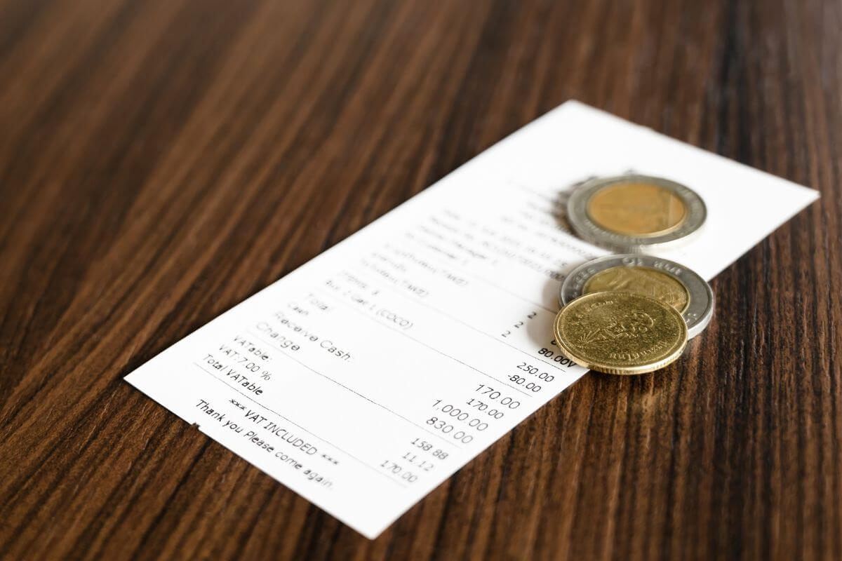The picture of a receipt and coins indicates to round up every purchase and save small amounts that add up to big progress.