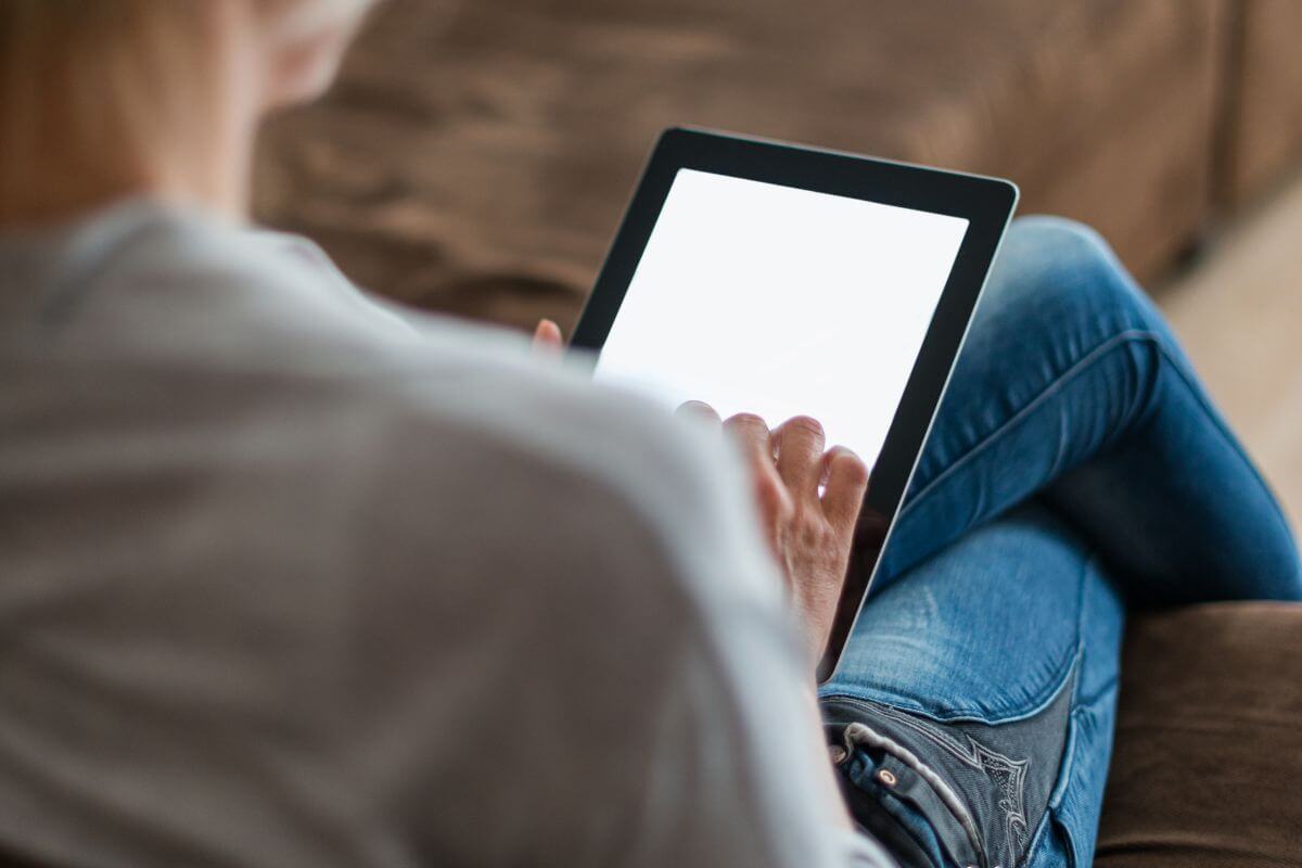 The photo of a girl using a tablet device means using a subscription tracker to cancel unused services and free up money for important goals.