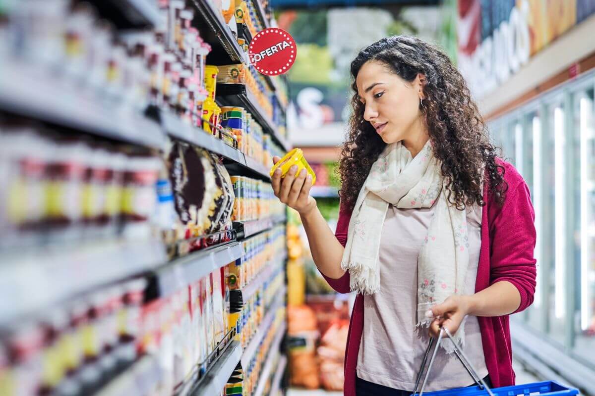The photo of a girl holding a cart while picking up goods to choose from in a store referring to avoiding unnecessary purchases helps you focus on what truly matters.