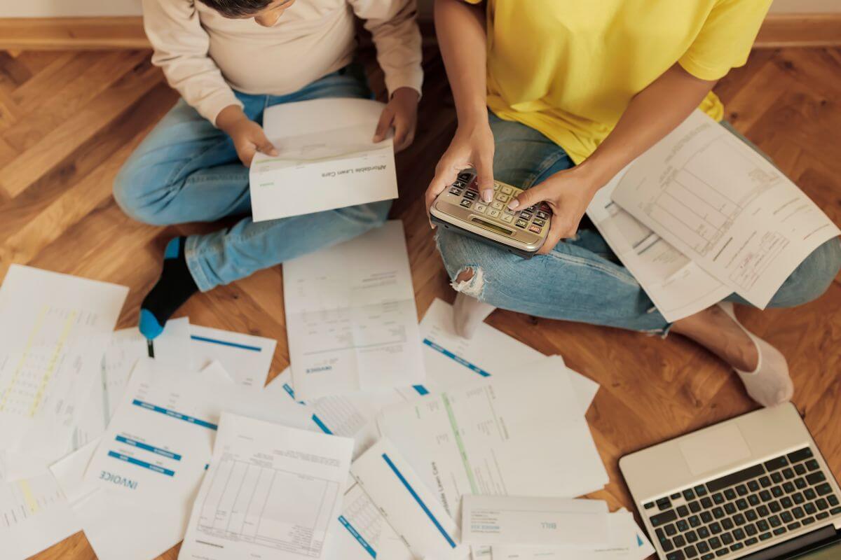 The picture tells about papers, a laptop, and a couple calculating and looking at the documents which indicates to use the debt avalanche method that helps to save you money on interest and helps you get out of debt faster.