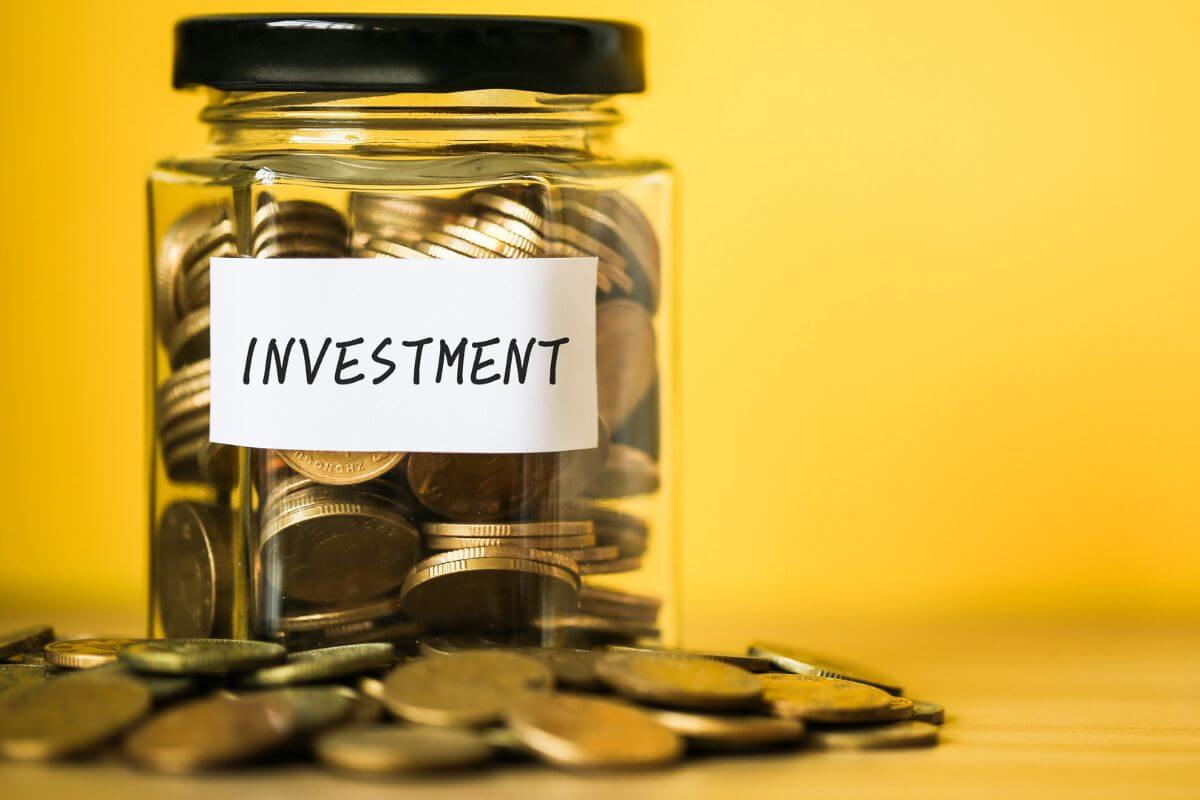 The image shows coins around and a jar filled with coins and notes referring to investing in fractional shares to start investing without needing a lot of money.
