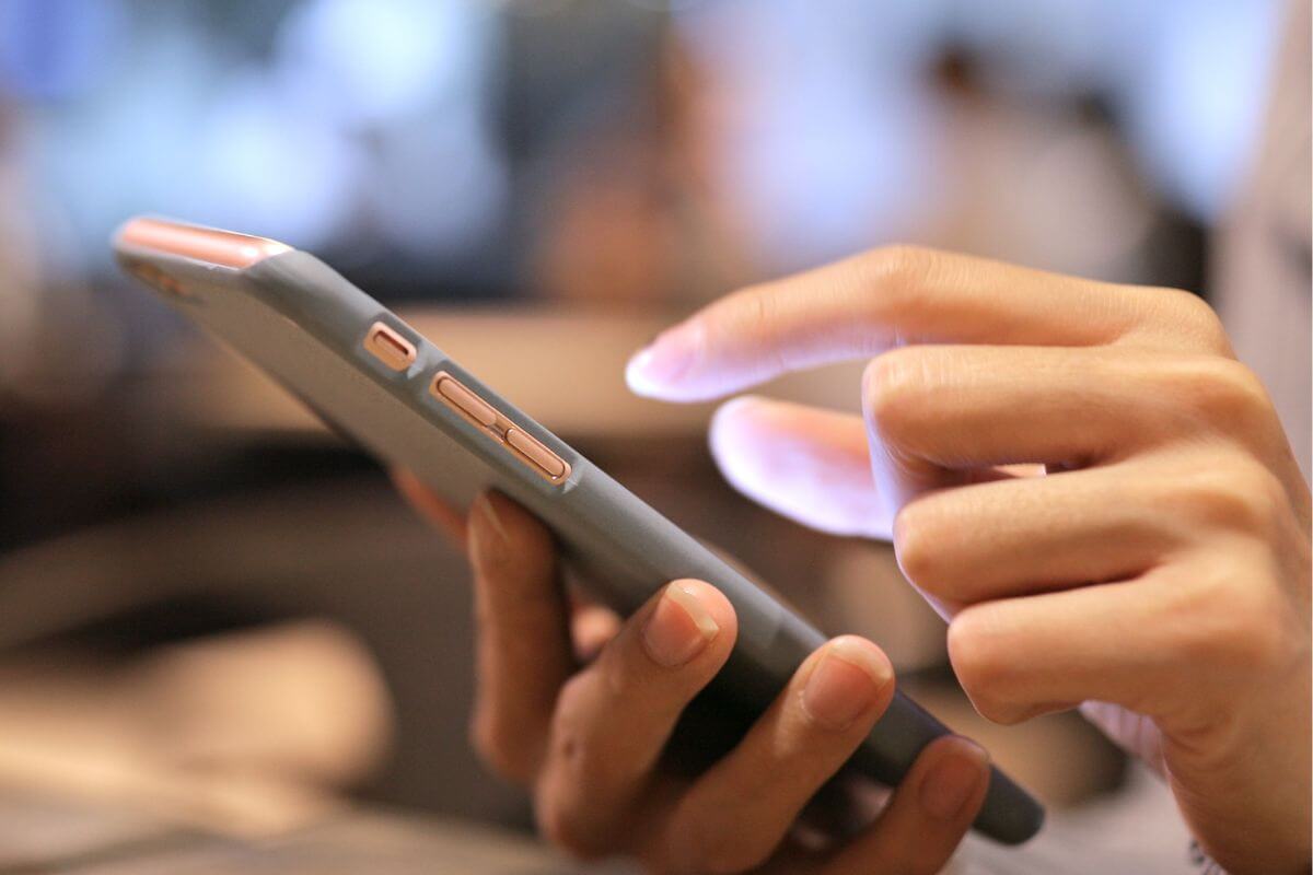 The picture of a girl's hand using a smartphone represents an experiment with micro-investing platforms that help grow your money in the long run.