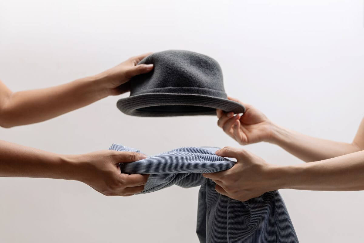The image of two hands exchanging stuff together indicates participating in community swaps of goods or services without spending cash.