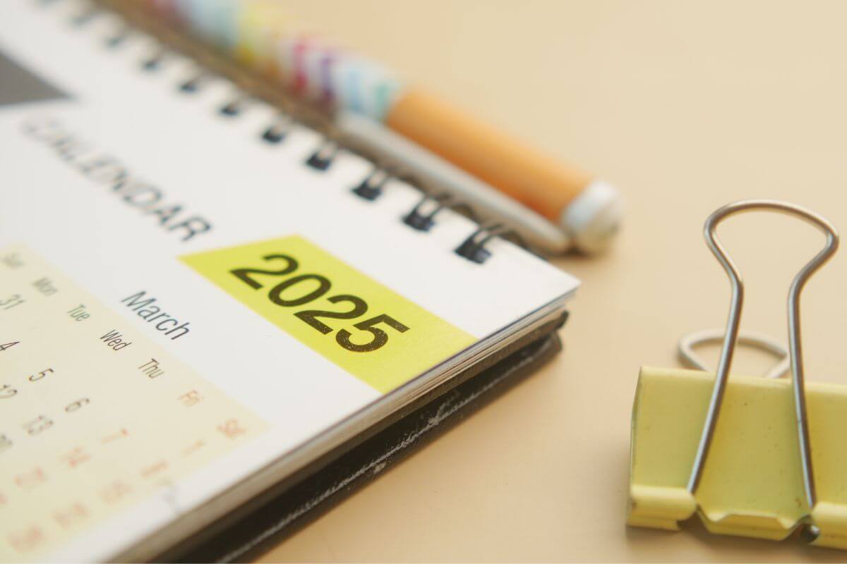 The photo tells about a clip, a pen, and a calendar which means to start 2025 with proper money bliss advice and make this the year you take control of your money.