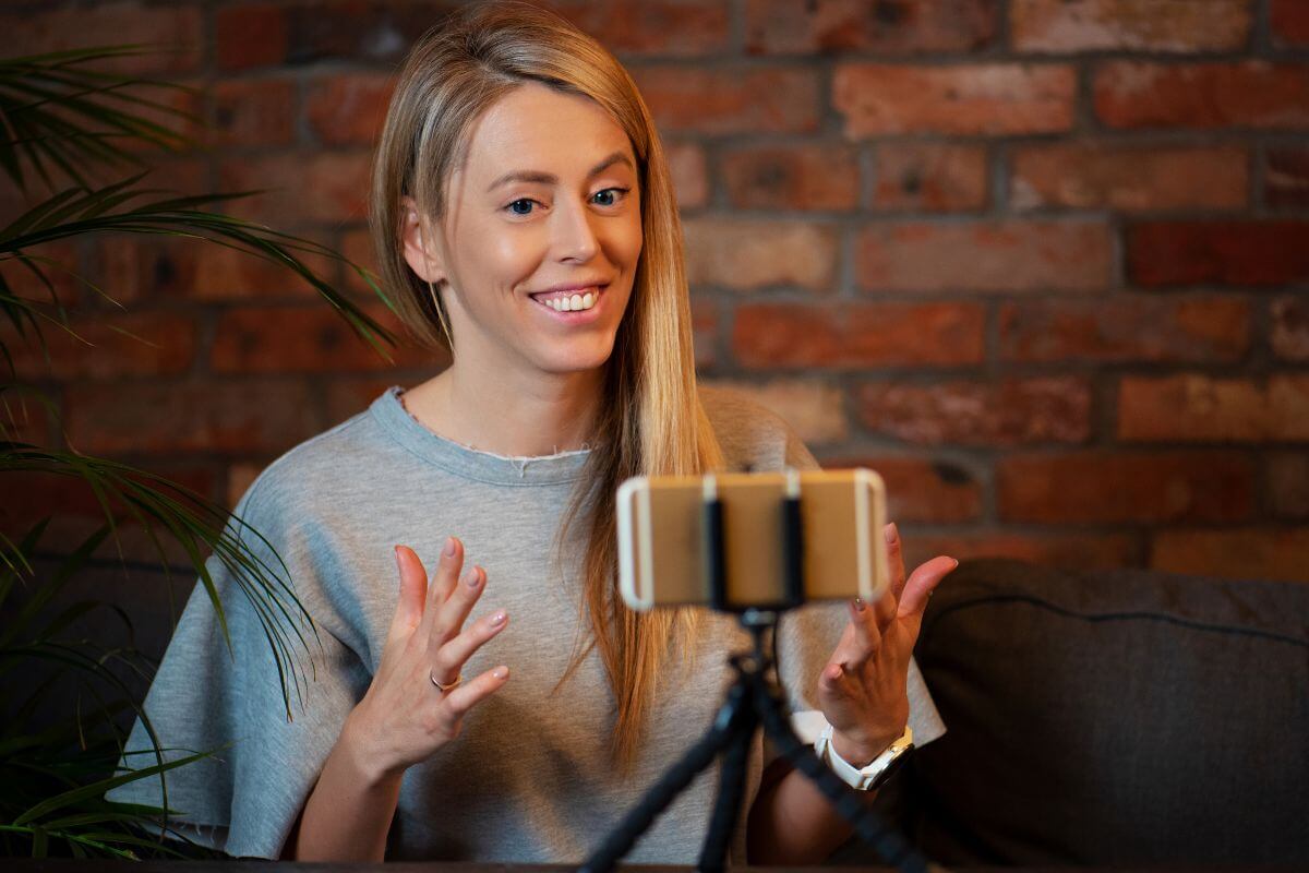 The photo shows a girl filming herself on her phone to start a niche blog channel with affiliate income to earn money while building a following and doing what you loves.