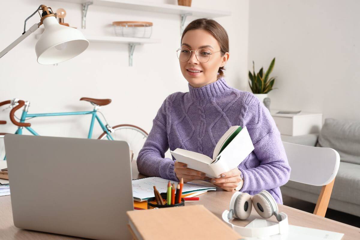The picture shows a headset, notebooks, pens a bike, and a girl holding a book while looking at the laptop refers to teaching a unique skill through virtual classes to help others learn while earning extra income.