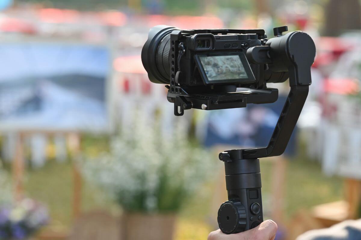 The photo tells about a man's hand holding a camera indicating to offer videography services and turn it into a money-making tool.