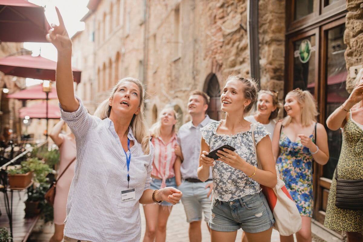 The photo of a tourist guide and a group of tourists on the street refers to hosting local tours for tourists to connect with people and earn extra cash.