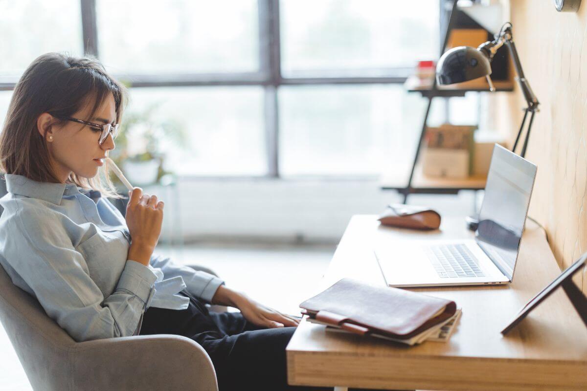 The picture of a laptop, a lamp, a notebook, and a girl sitting on a chair while thinking deeply which refers to visualizing the successful outcome helps you stay connected to why the goal matters.