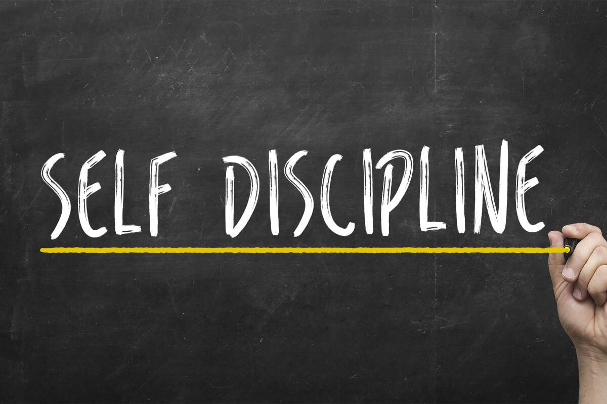 The picture of a blackboard with notes and a man's hand holding a yellow marker which indicates to commit to self-discipline and staying resilient through setbacks helps you bounce back when challenges arise.