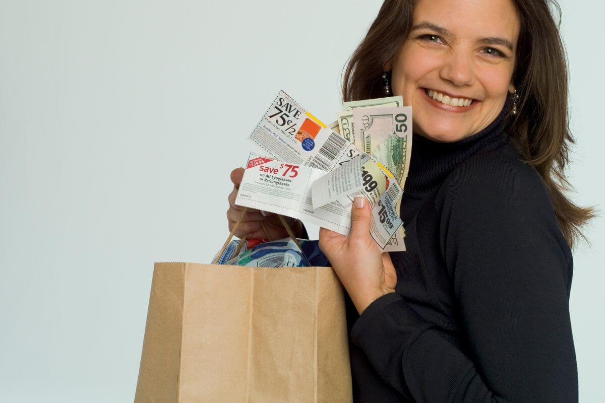 The photo shows a girl holding a shopping bag, coupons, and dollar bills which refers to using coupons and cashback apps, an easy way to cut costs without changing your shopping habits too much.