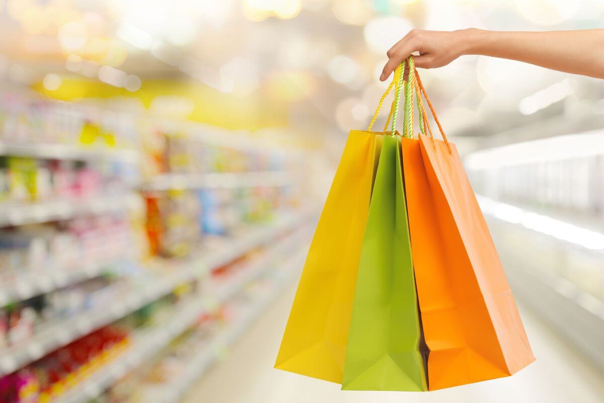 The picture tells about product displays and a girl's hand holding shopping bags indicating that limiting impulse buying helps you make smarter spending choices.