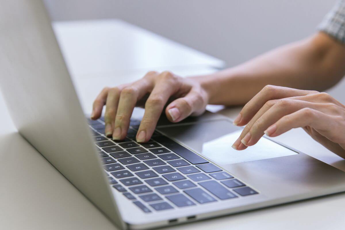 The photo shows a girl's hand using a laptop indicating to find more thrifty habits to explore and cut down costs and save money.