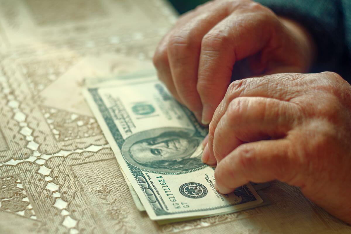 The picture shows an old hand holding dollar bills which means making a smaller and more consistent contribution for more manageable and still building significant savings over time. 