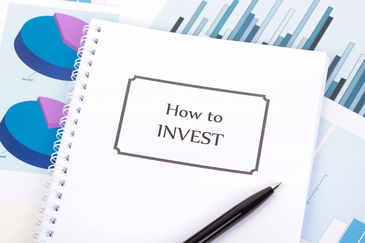 The picture tells about a paper with graphs, a pen, and a manual with notes to learn more about how to invest for retirement and keep your financial future on track.