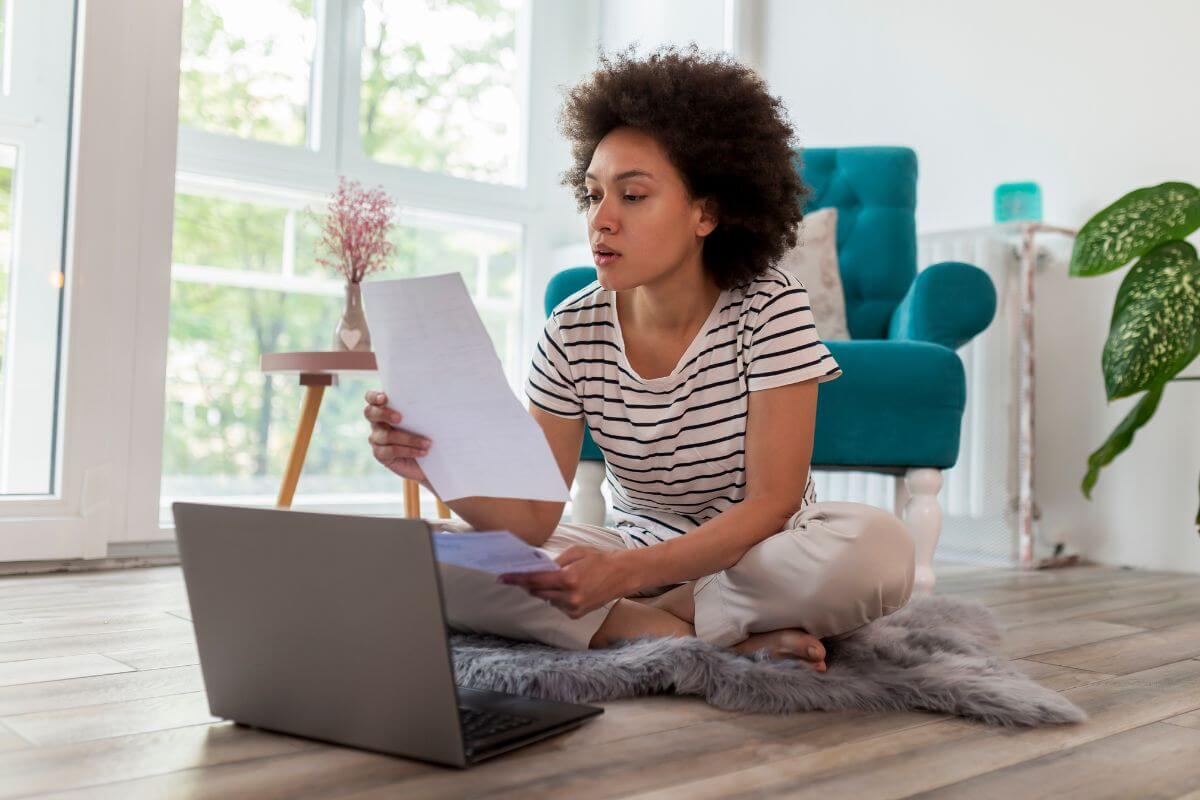 The image shows a laptop and a girl holding papers indicating that focusing on paying off high-interest debt first saves you money over time by reducing the amount you pay.