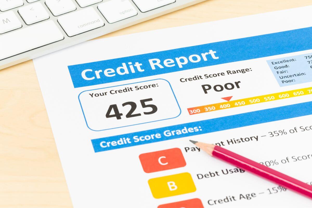 The photo shows a keyboard, a pen, and a piece of paper with notes and labels which means monitoring your credit report helps you stay motivated and ensures you're on the right path to becoming debt-free.