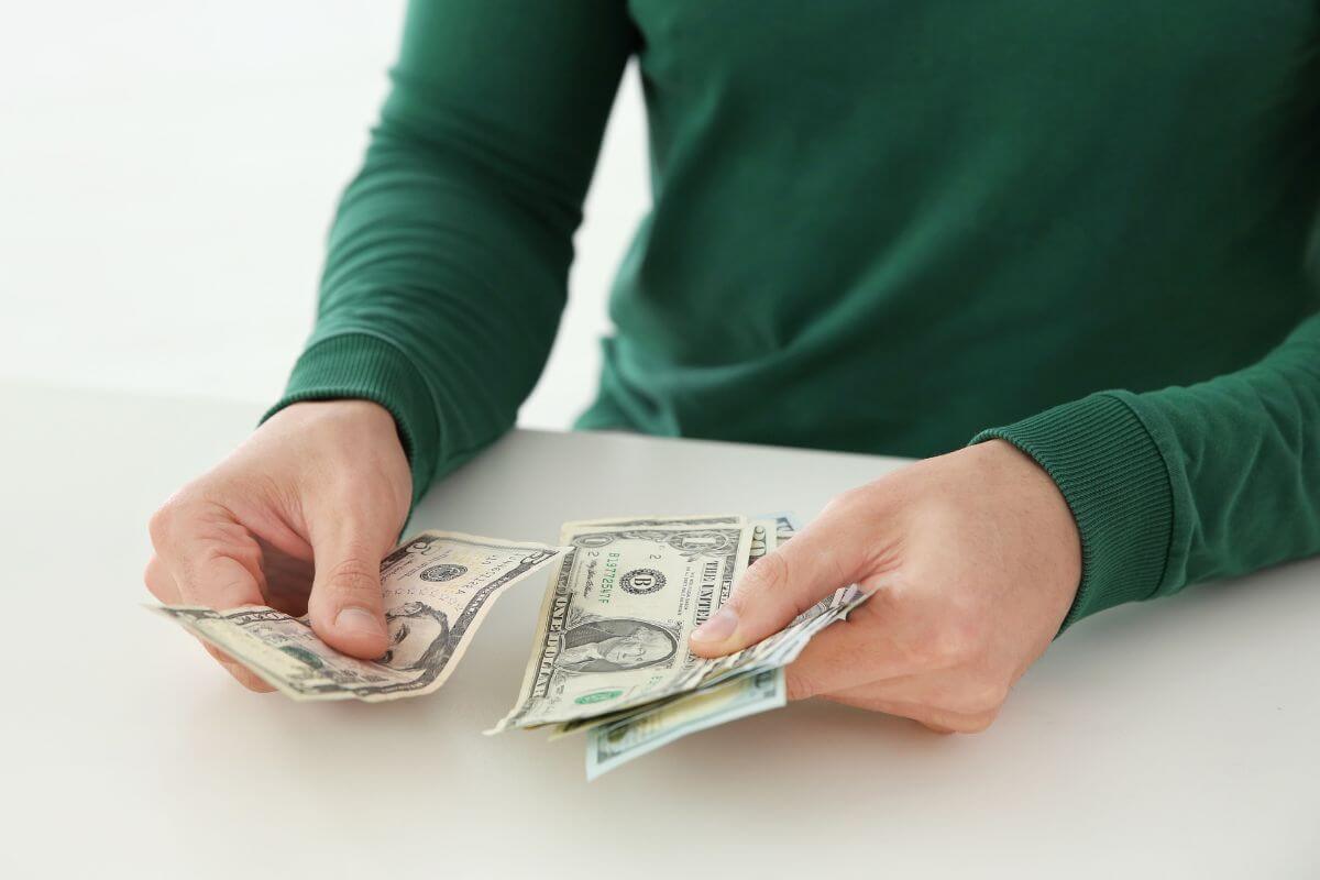 The picture shows a man's hand counting dollar bills which means to prioritize your money situation first to strengthen your money situation.