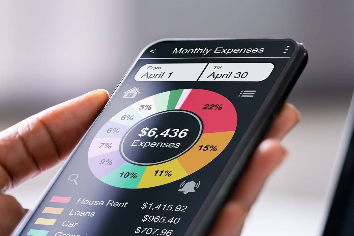 The photo shows a girl's hand holding a phone with a screen display which refers to using a spending tracker app can help you adjust and save more easily.