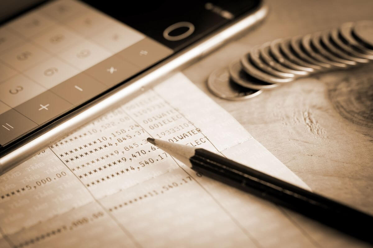 The image tells about coins, a phone with a calculator app, a pen, and a bank book with numbers referring to setting up an automatic transfer to a savings account after payday.