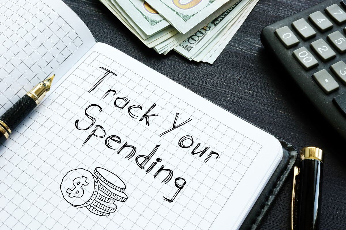 The photo of dollar bills, a calculator a pen, and a notebook with notes which means to track your spending per hour worked can help you make smarter buying decisions.