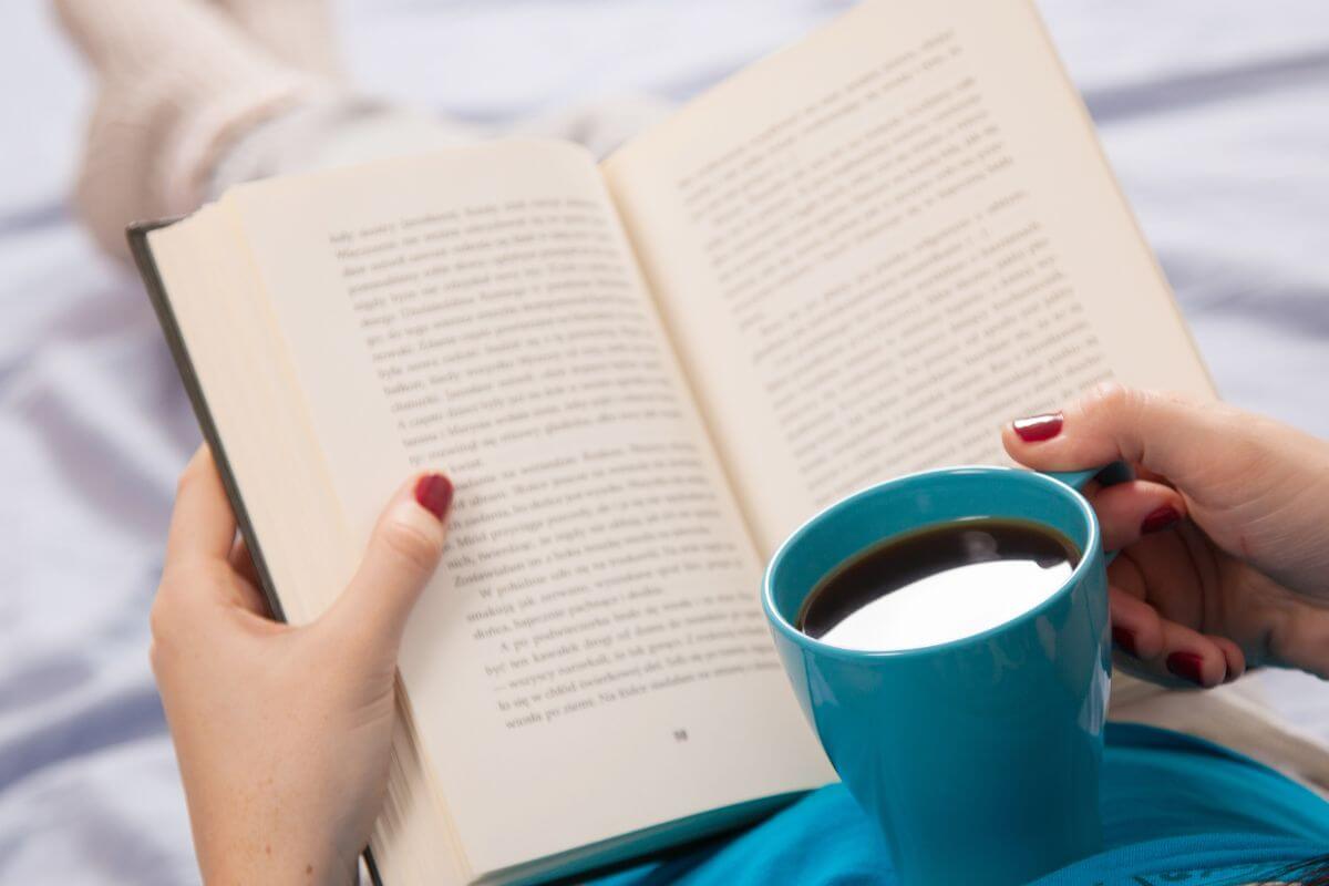 The image of a girl having a coffee while reading a book indicating to start reading more about personal finance helps you make smarter financial decisions.