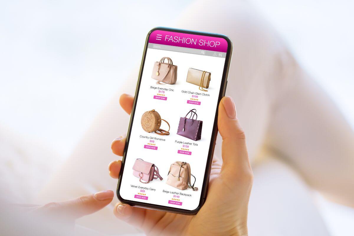 The photo tells about a girl's hand using a phone for online shopping for expensive bags which means avoiding lifestyle inflation as your income increases to grow wealth and reach financial freedom.