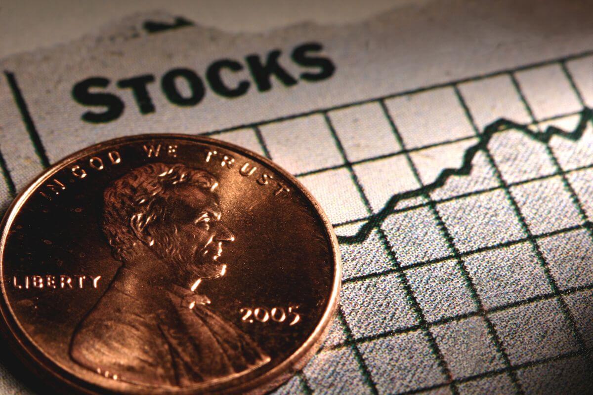 The photo of a coin and a piece of paper with a graph and a note means to make investing in stocks a priority to achieve financial freedom.