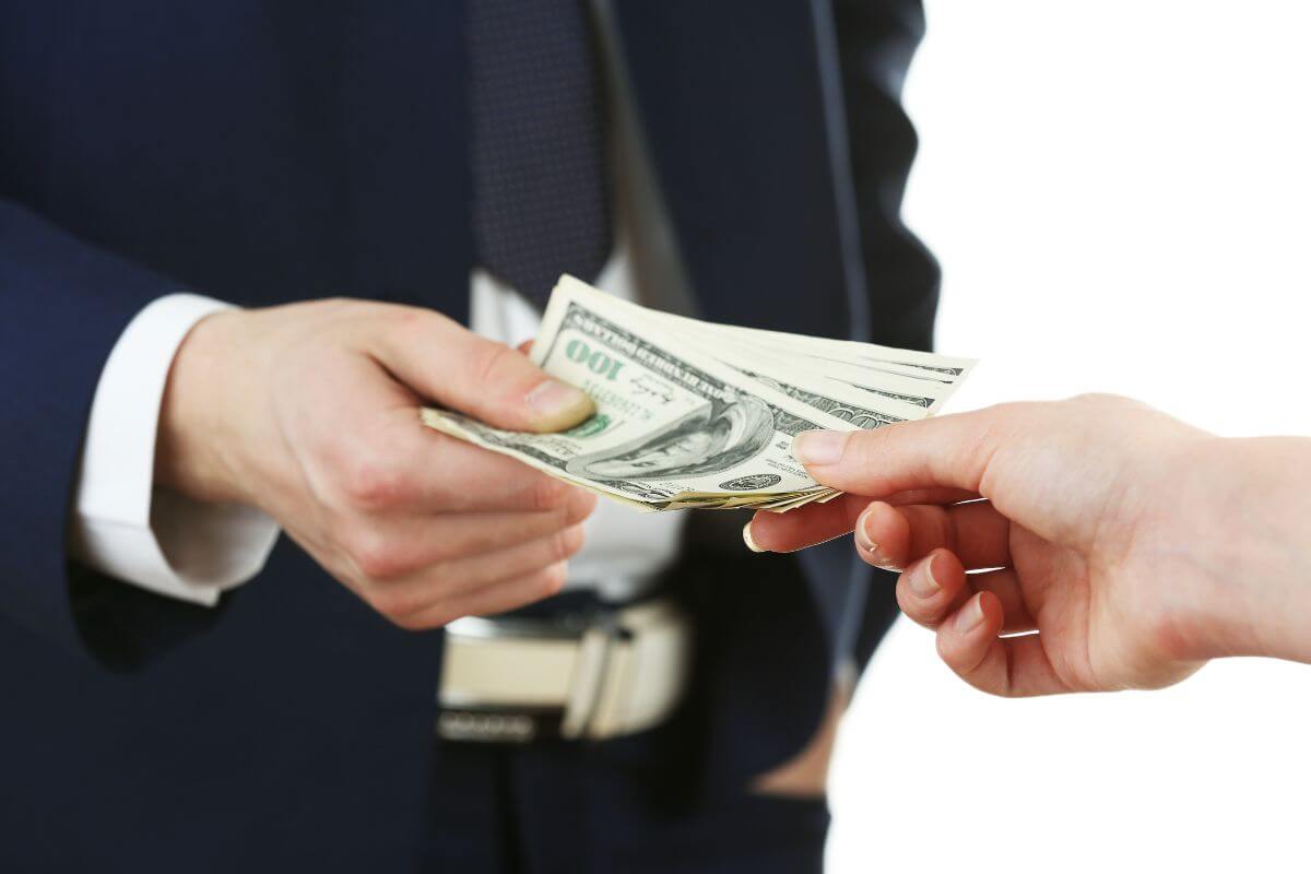 The photo shows a man in a suit handing dollar bills to the girl, referring to borrowing money without formal terms, which can lead to a lack of clear repayment that causes conflicts and damages trust between both parties.