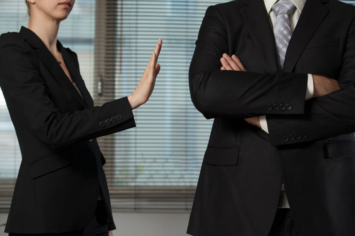 The image shows a man crossing his arms and a girl doing a stop sign on him referring to borrowing money blurs boundaries between personal and financial matters that often lead to awkward situations in social interactions.