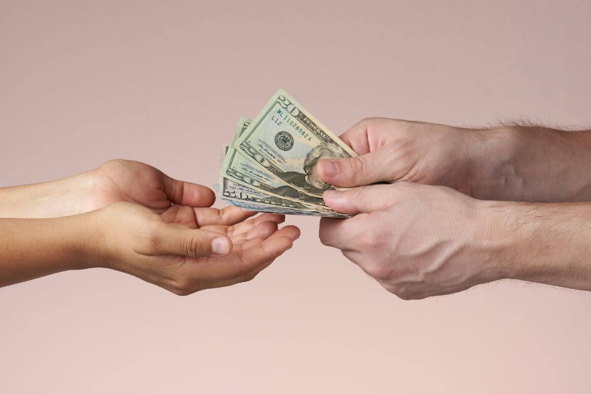 The photo shows a man's hand giving money to the girl's hand referring to how borrowing money can lead to repeated borrowing cycles that keep you stuck and stops you from achieving financial independence. 