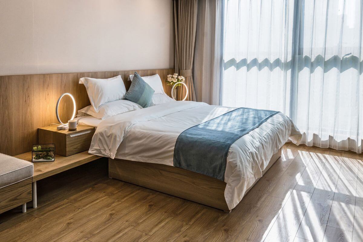 The image shows a bed and other stuff referring to renting out a room in your home on Airbnb to turn it into income and reach your financial goals.