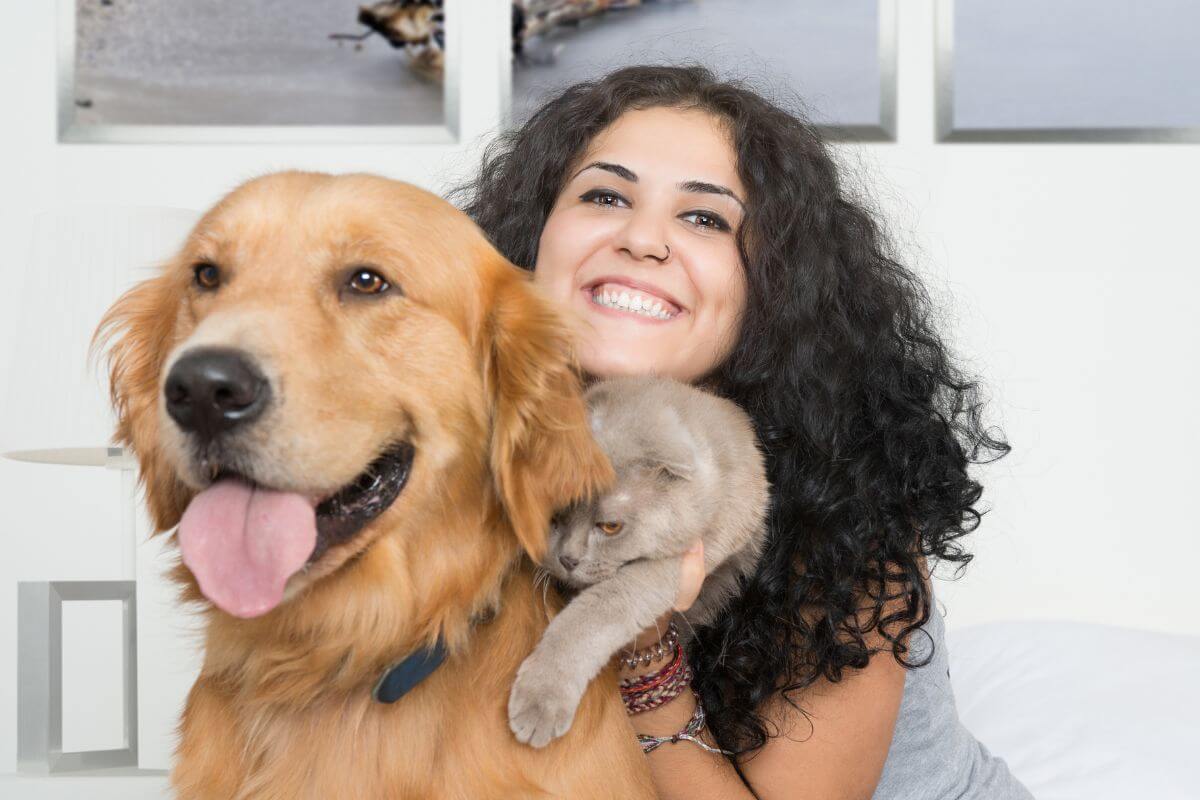 The photo tells about a dig, a cat, and a girl embracing them indicating to offer pet-sitting services to makea money while spending time with furry friends.