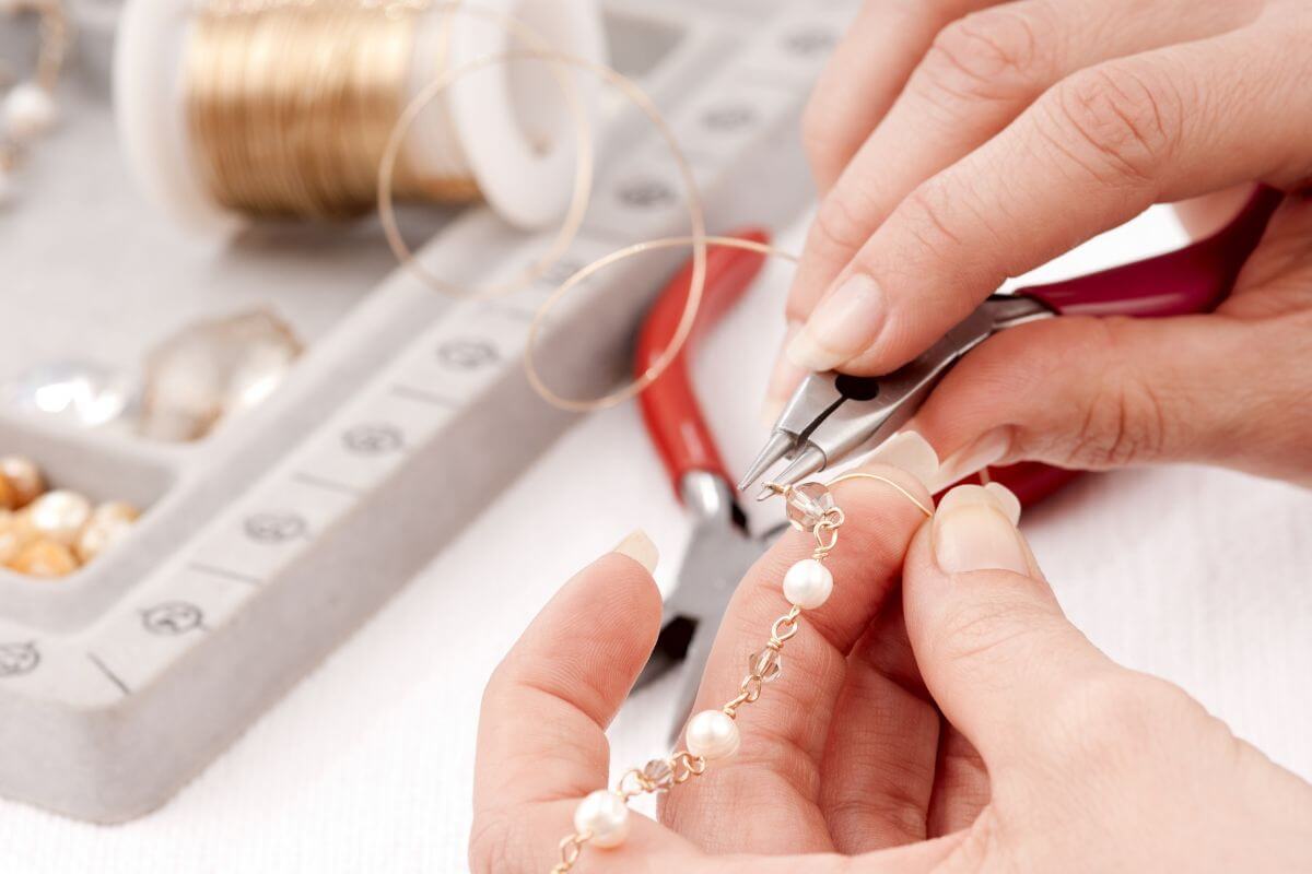 The image of craft supplies and a girl twisting the wire to make a bracelet indicating to sell handmade crafts on Etsy to share your talent and boost your earnings.