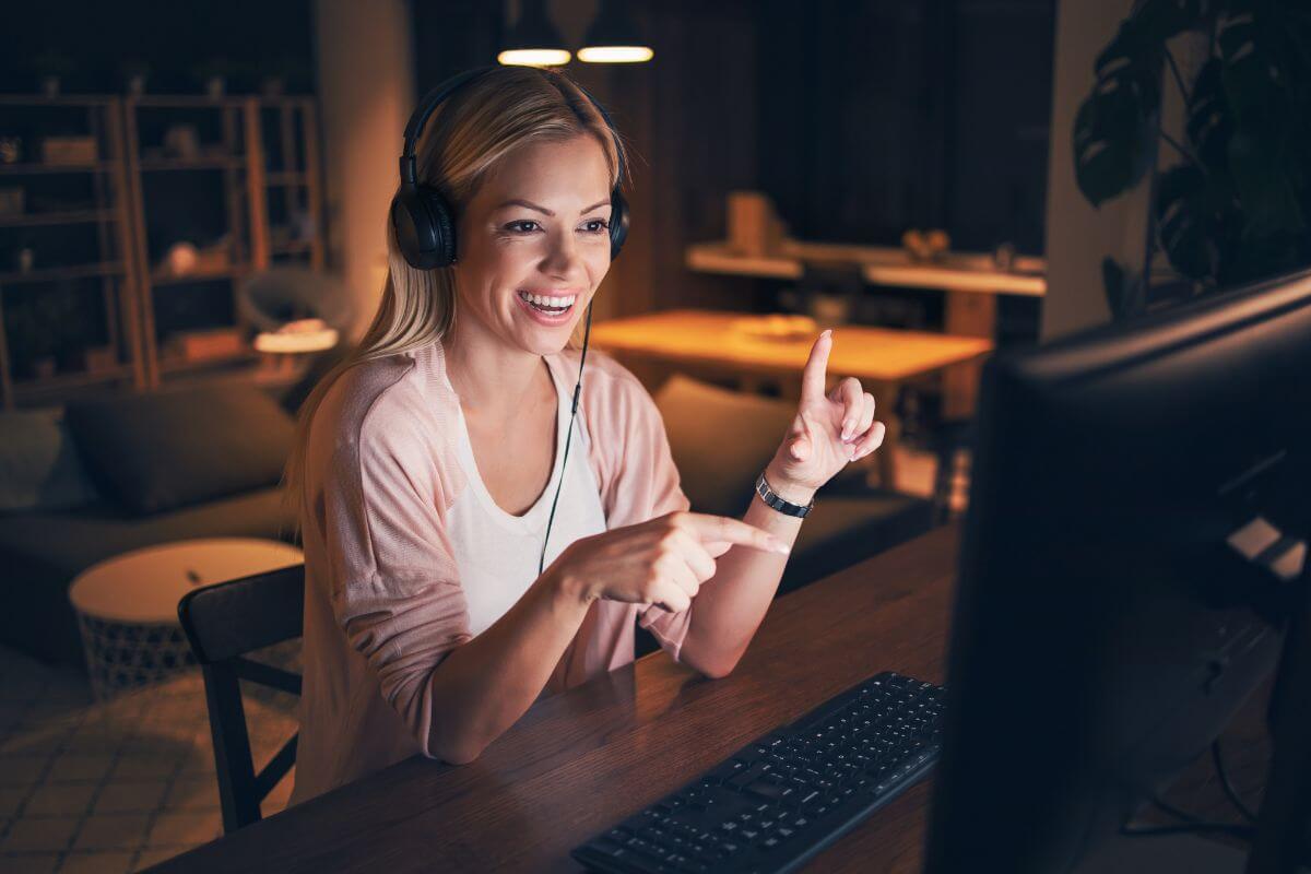 The image shows a girl working on her computer while using a headset indicating to teach a skill online through platforms to earn money from what you know.
