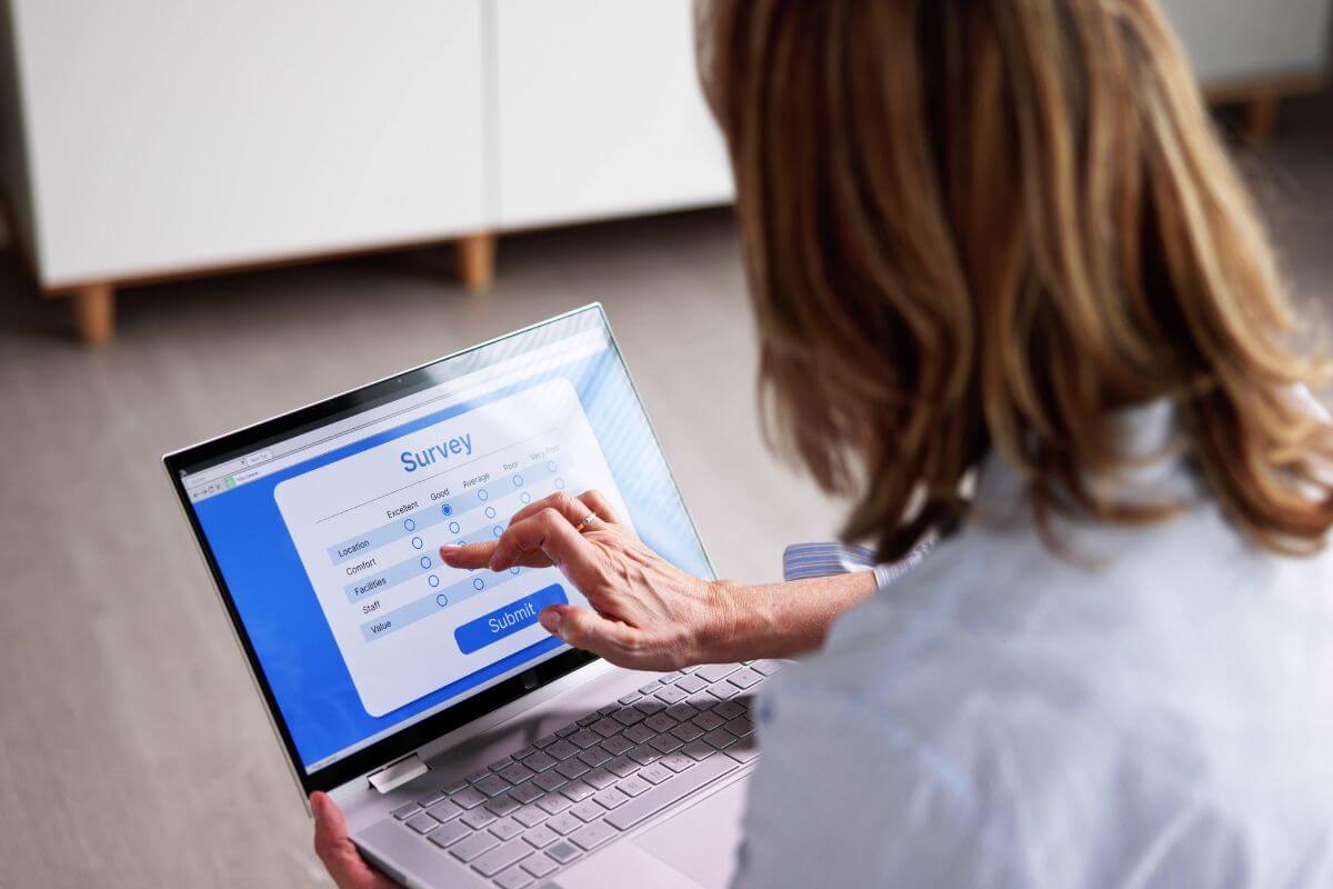 The image of a girl tapping the screen of her laptop with a screen display indicating her participation in online surveys to earn quick cash with minimal effort.
