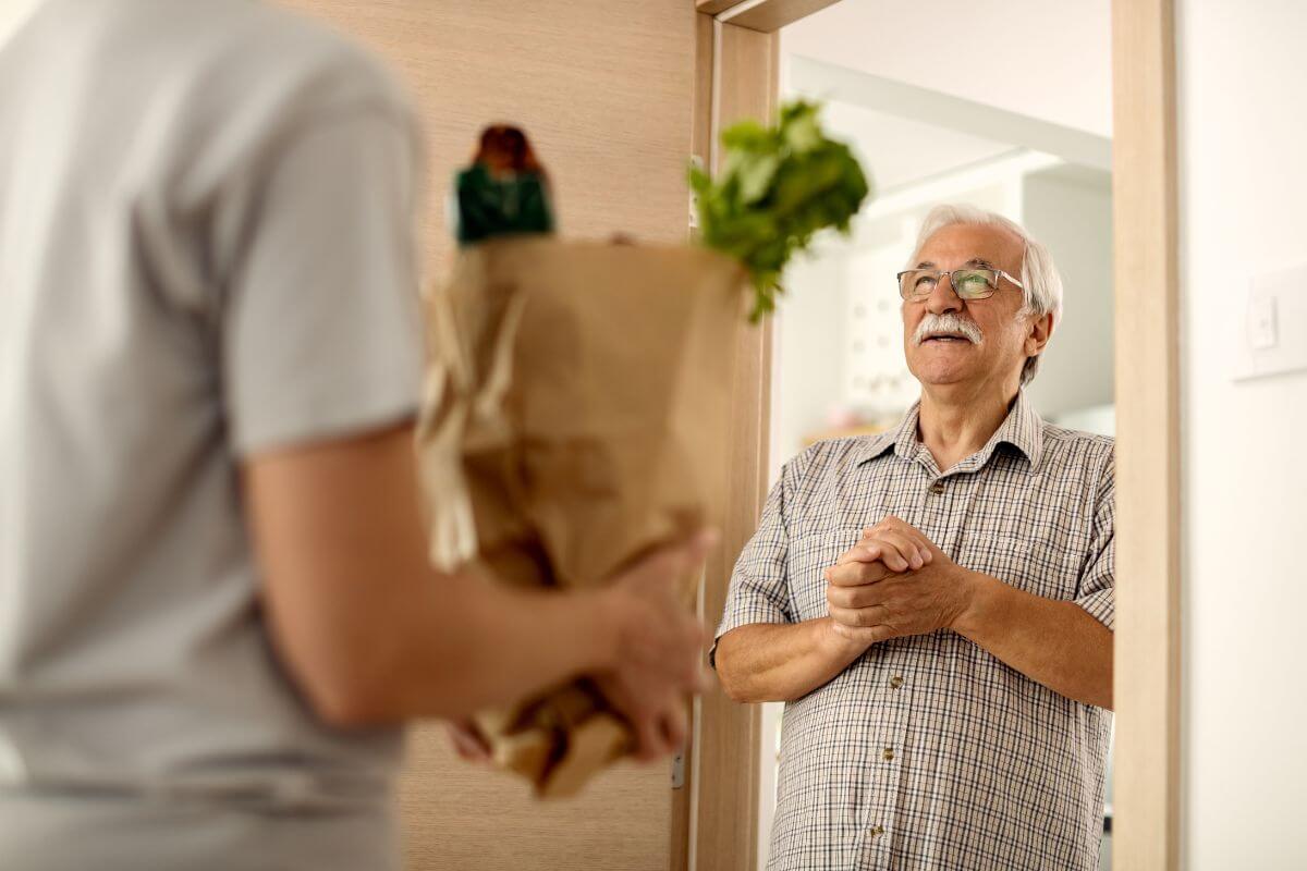 The image tells about a man holding a paper bag with groceries inside and handing it to the old man waiting at the door which means to offer local errand-running services that keep you active while making money.