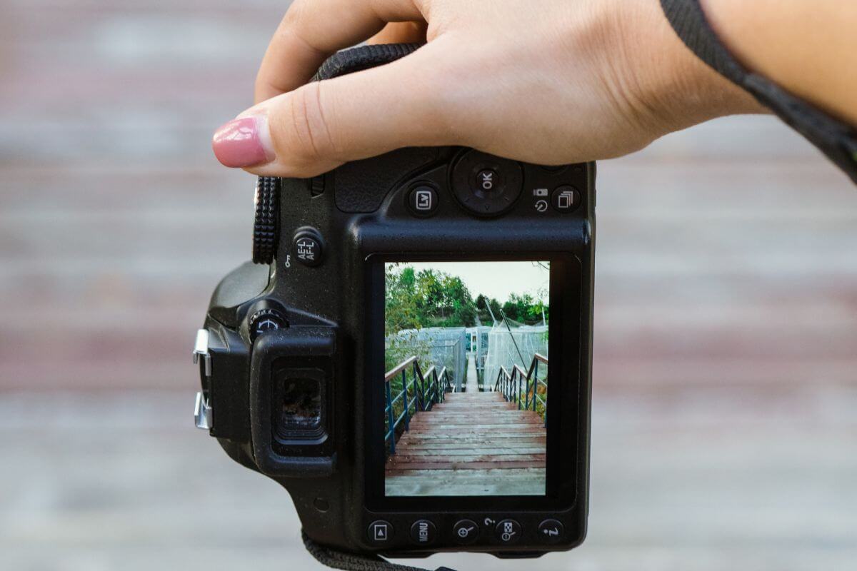 The image tells about a girl's hand holding a camera and capturing the beautiful view of the bridge to sell stock photos to content platforms to earn from your photography skills.