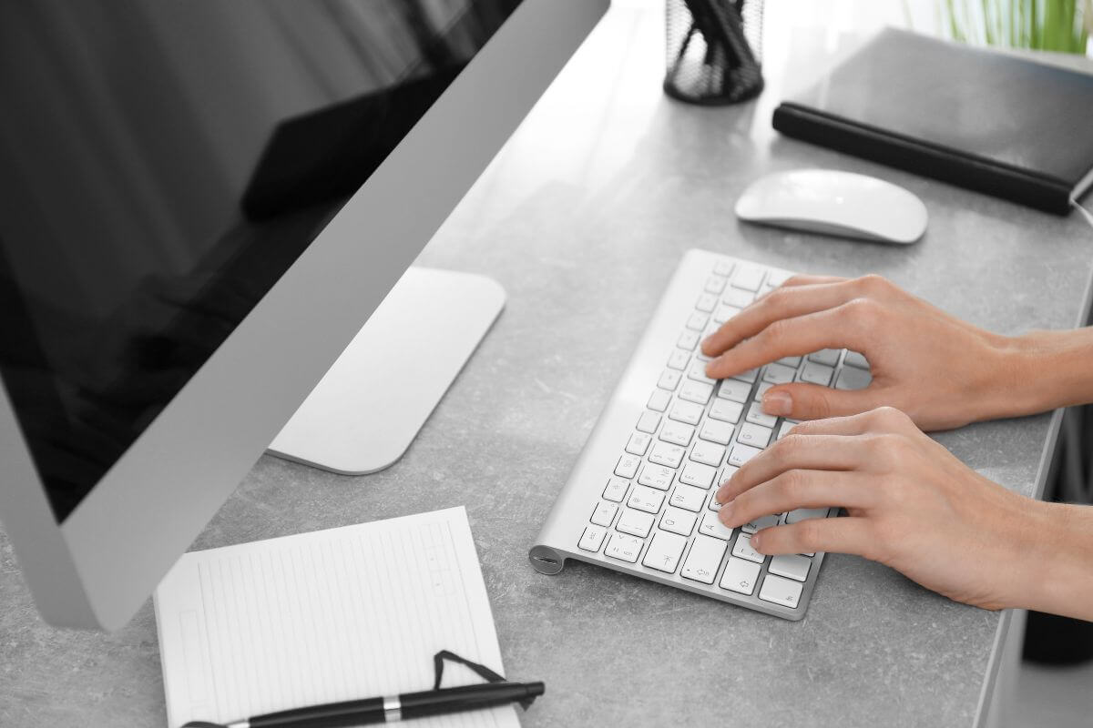 The Picture of notebooks, a pen, a mouse, a monitor, and a girl typing on the keyboard refers to offering tech setup services to make quick cash.