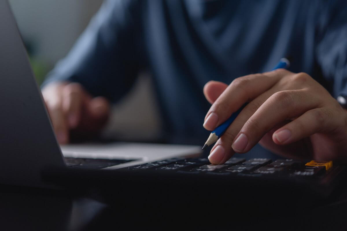 The picture of a man's hand using a laptop while using a calculator indicates to use of budgeting tools to stay organized and help you stick to your budget.