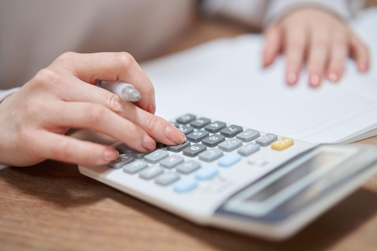 The photo tells about the girl calculating while referring to the papers indicating to review and adjust your budget regularly to keep everything balanced and on track.