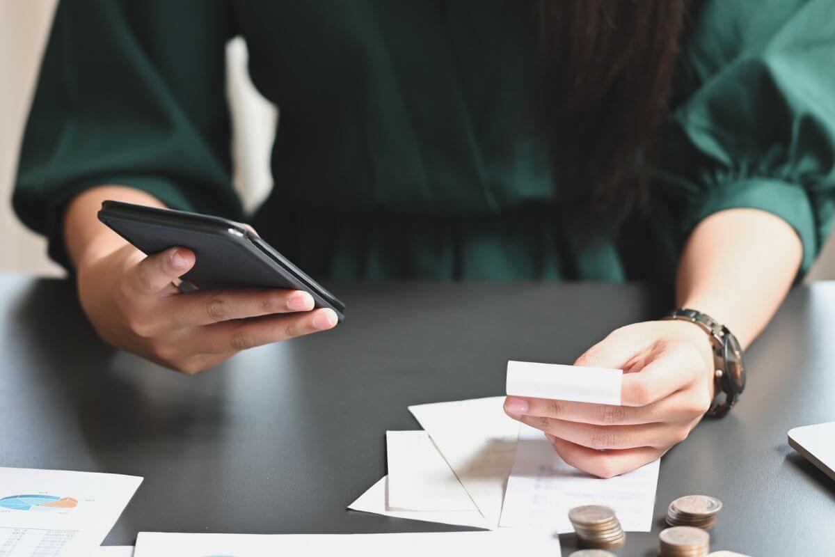 The image of coin stocks, papers on the table, and a girl calculating the receipts to stick to the plan and track spending helps you build smarter money habits over time.