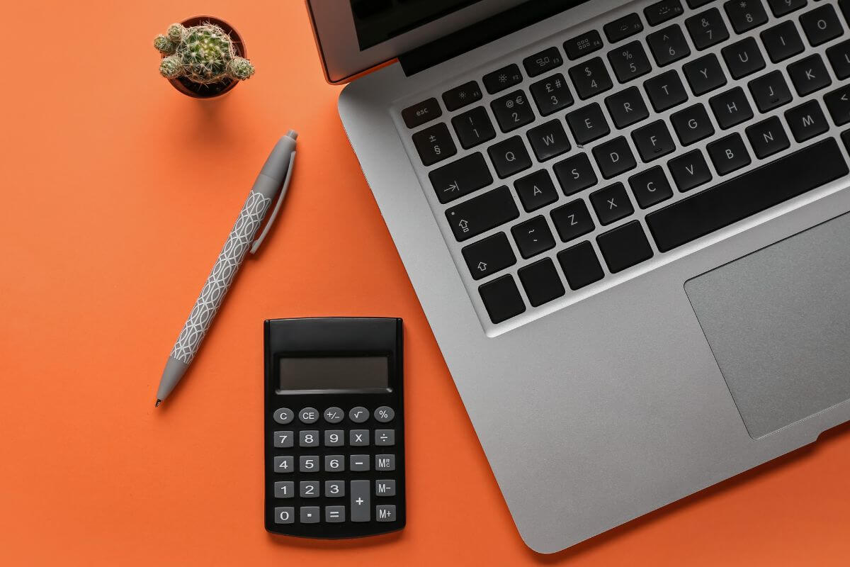 The photo of a cactus, a pen, a calculator, and a laptop refers to creating your budget template today to take control of your money and plan for your future.