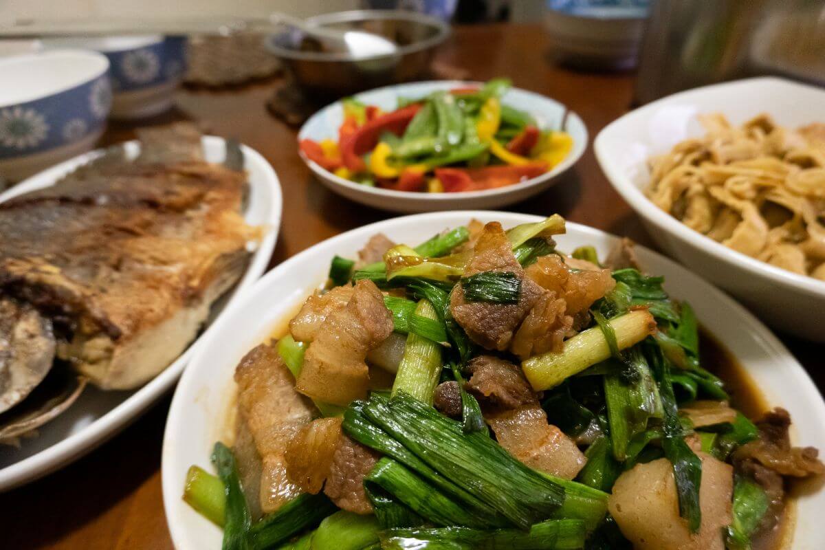 The image shows different varieties of meals on the tables indicating to limit dining out and focus on affordable home-cooked meals to cut spending and grow your savings.