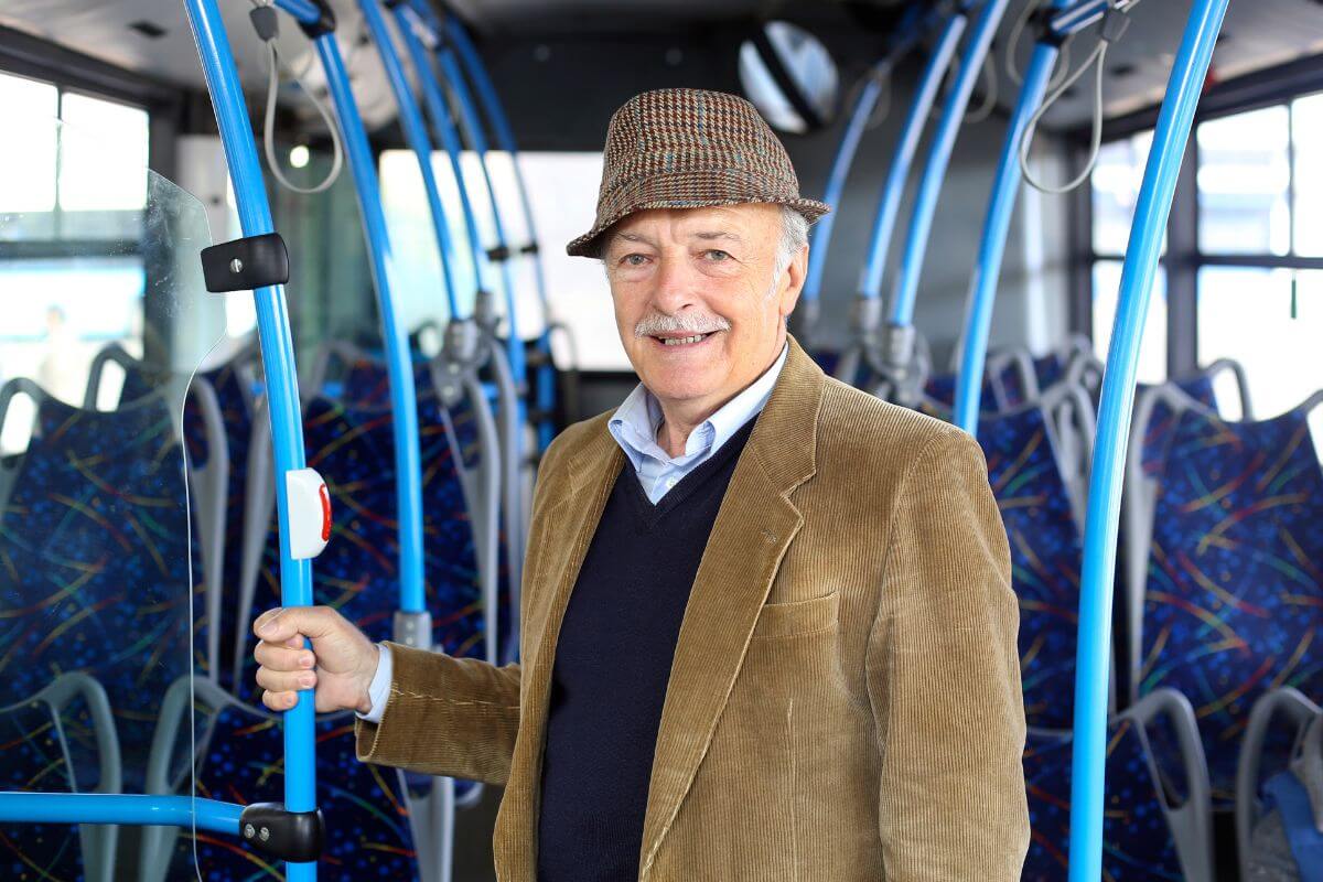 The image of a senior man standing inside a bus indicating to get discounted public transportation fares to save money.