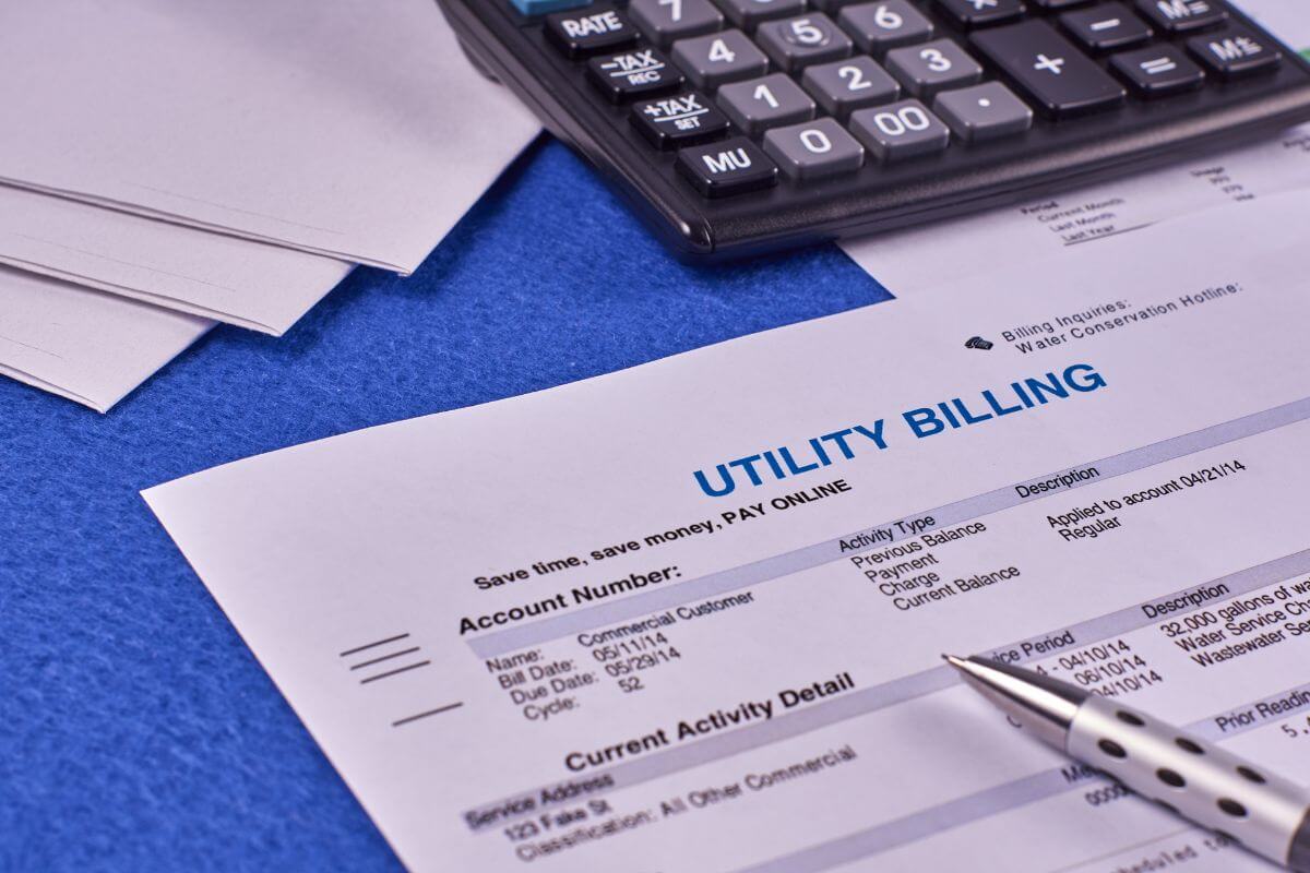 The photo shows papers, a calculator, a pen, and a piece of paper with notes referring to look for discounts on utility bills for seniors to manage living costs and keep bills more affordable.