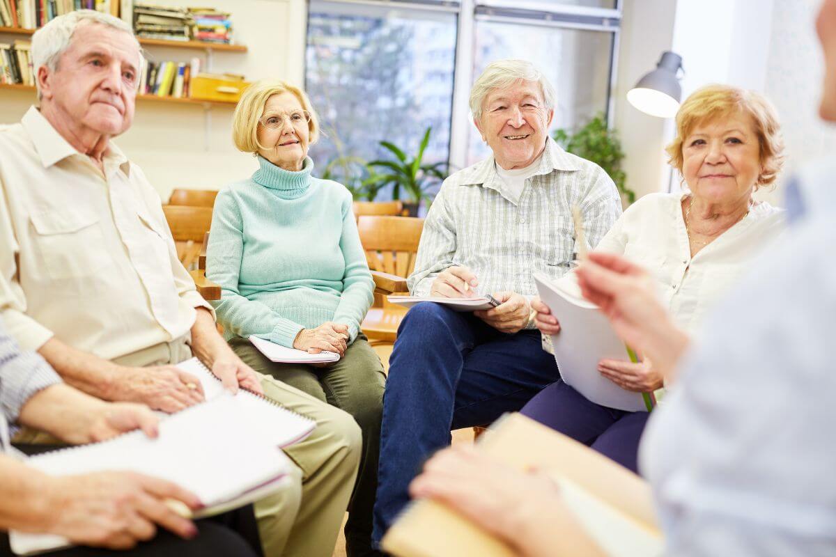 The picture shows senior groups holding manuals and having a session together referring to joining a senior club for exclusive deals can save money while expanding your social circle.