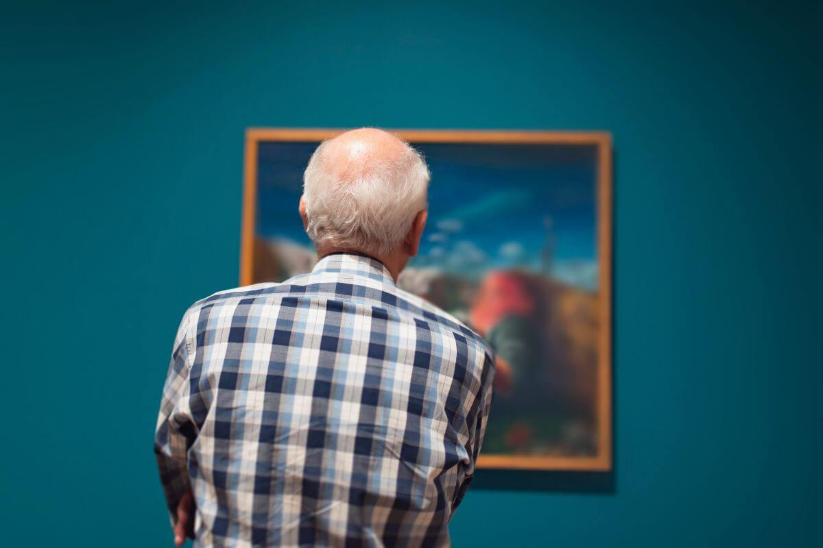 The picture of a senior looking at a painting inside a museum makes it easier to enjoy arts and culture while saving money.