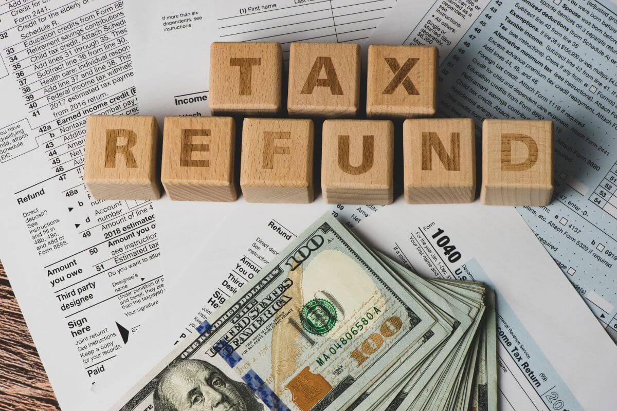 The image of papers on the table, wooden cubes with letters, and dollar bills indicating to invest windfall to savings to supercharge your financial goals.