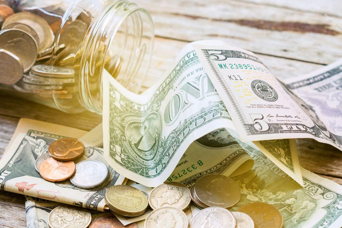 The photo of coins and dollar bills on the table, and a jar filled with coins which refers to automated savings makes it easier to save consistently.